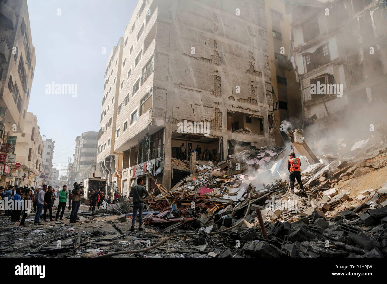 Difesa civile visto lo spegnimento di un incendio dopo un bersaglio dei sei piani in Gaza City. Foto Stock