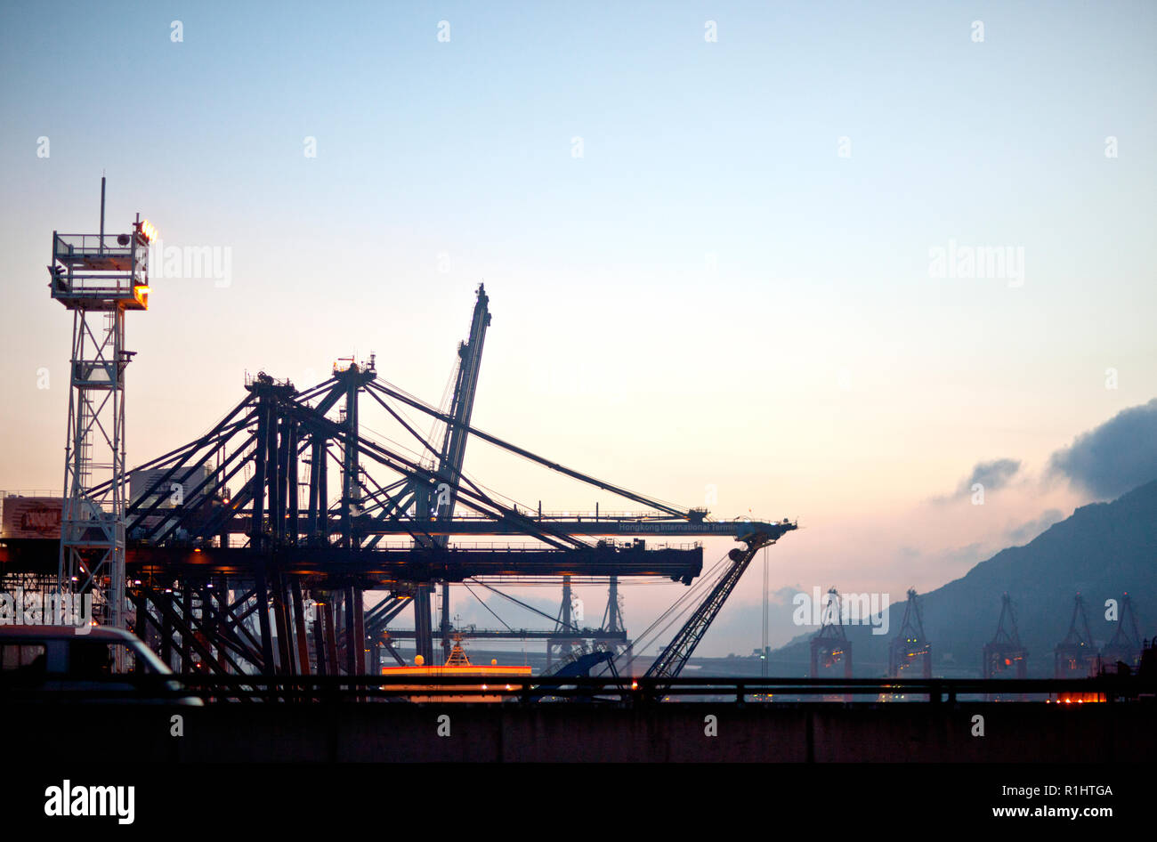Gru illuminata in un porto di spedizione al crepuscolo. Foto Stock