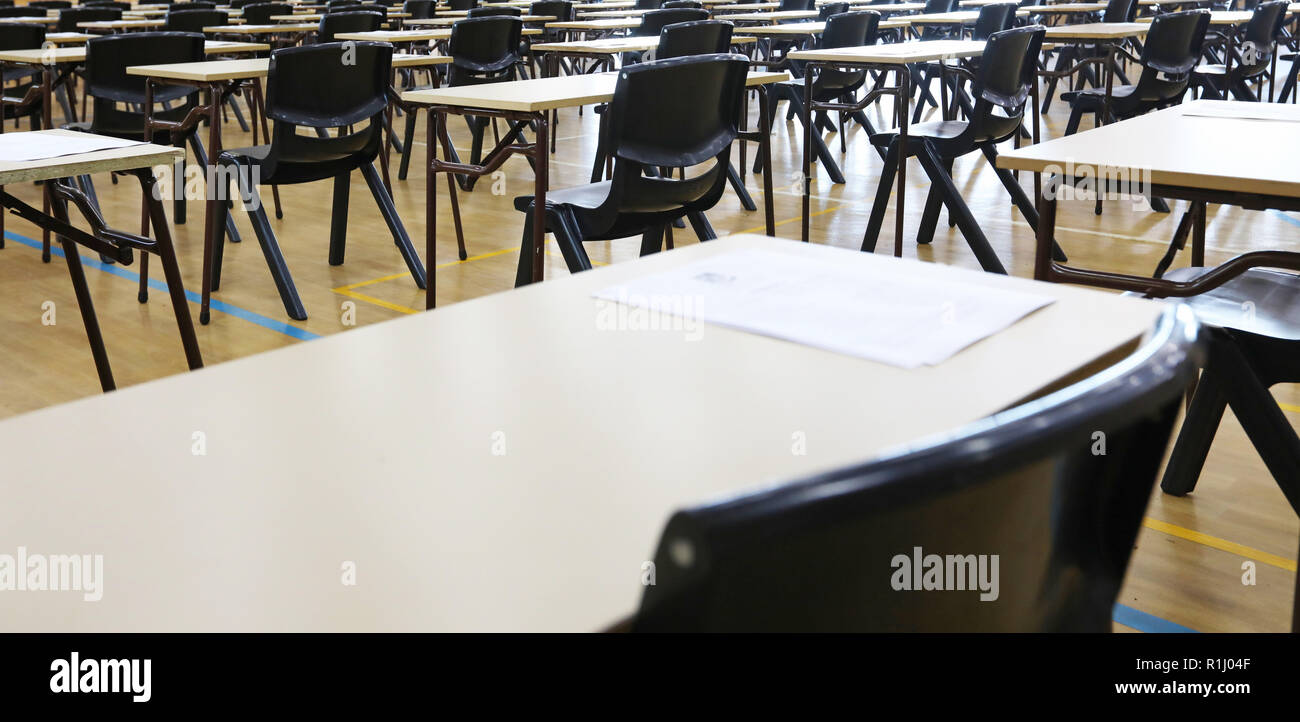 Vista di una grande sala esame sala esame e scrivanie tavoli allineati in file pronto per gli studenti di una scuola superiore di venire e sedersi i loro esami carta per prove Foto Stock
