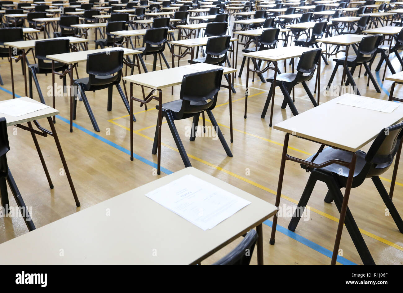 Vista di una grande sala esame sala esame e scrivanie tavoli allineati in file pronto per gli studenti di una scuola superiore di venire e sedersi i loro esami carta per prove Foto Stock