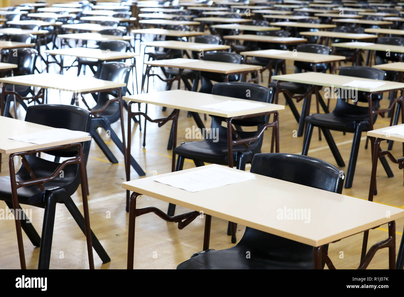 Vista di una grande sala esame sala esame e scrivanie tavoli allineati in file pronto per gli studenti di una scuola superiore di venire e sedersi i loro esami carta per prove Foto Stock