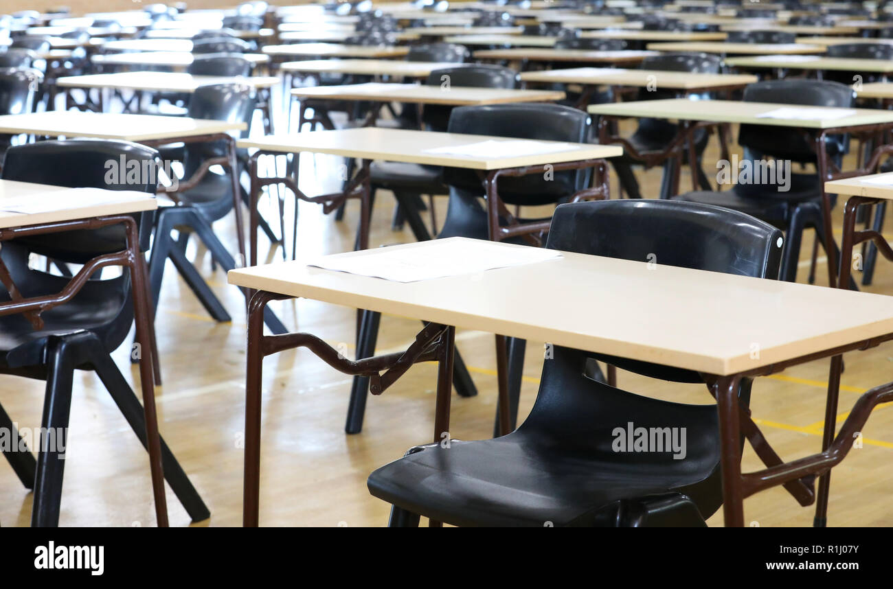 Vista di una grande sala esame sala esame e scrivanie tavoli allineati in file pronto per gli studenti di una scuola superiore di venire e sedersi i loro esami carta per prove Foto Stock