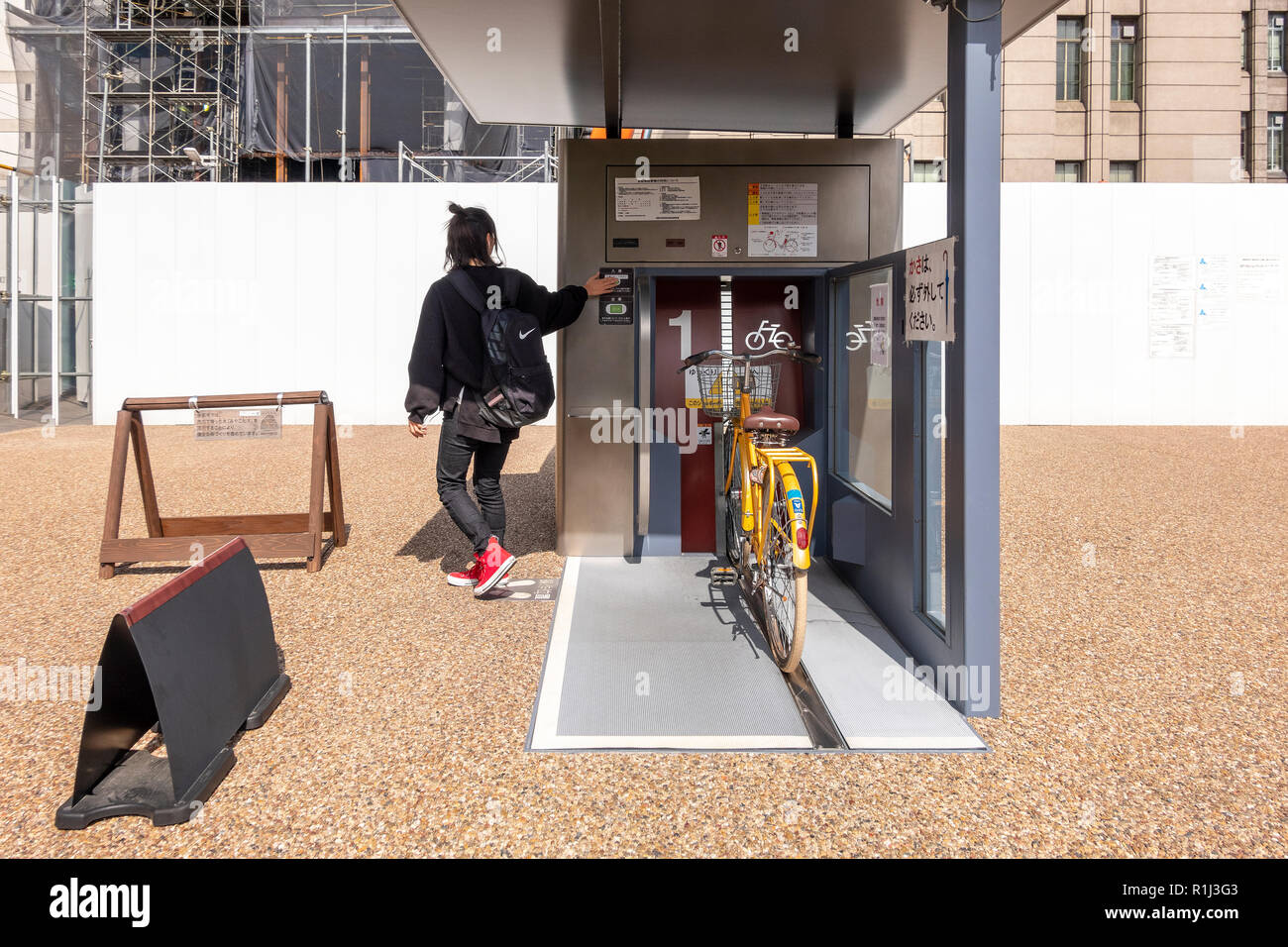 Parcheggio ragazza il suo moto in un Giken Eco ciclo metropolitana automatizzata il parcheggio per le bici davanti a Kyoto City Hall, Giappone. Serie di 3 immagini Foto Stock