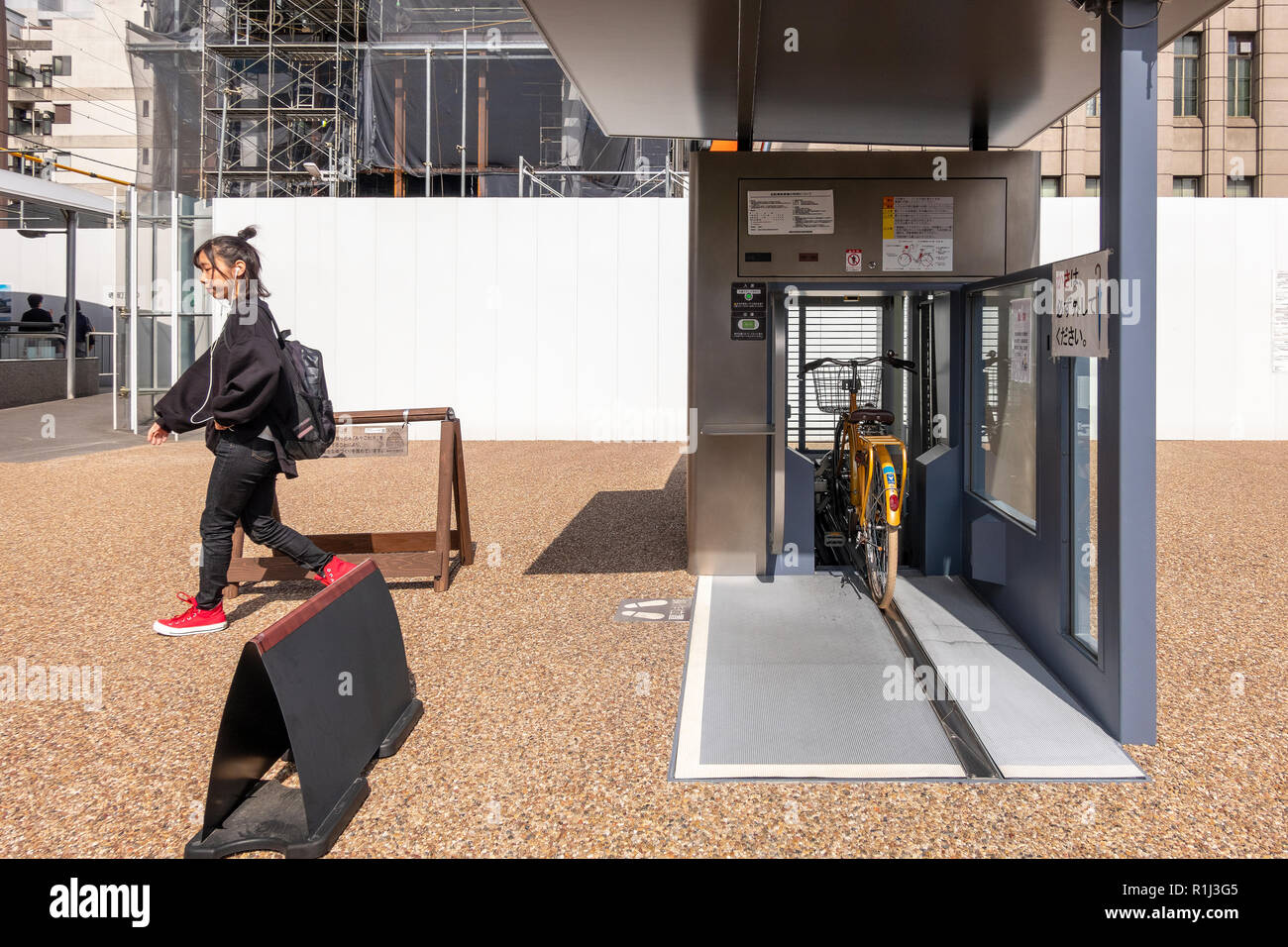 Parcheggio ragazza il suo moto in un Giken Eco ciclo metropolitana automatizzata il parcheggio per le bici davanti a Kyoto City Hall, Giappone. Serie di 3 immagini Foto Stock
