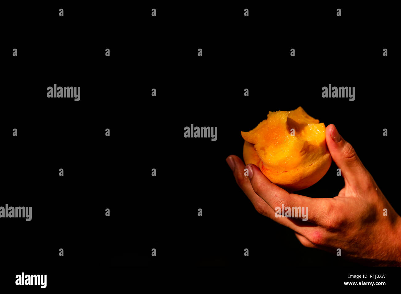Succosa morso peach catturati a mano su sfondo nero Foto Stock