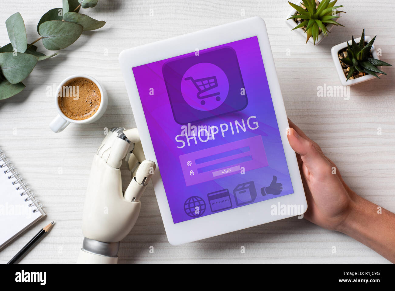 Immagine ritagliata dell uomo con protesi mano con tavoletta digitale con lo shopping sullo schermo a tavola con la tazza di caffè in ufficio Foto Stock