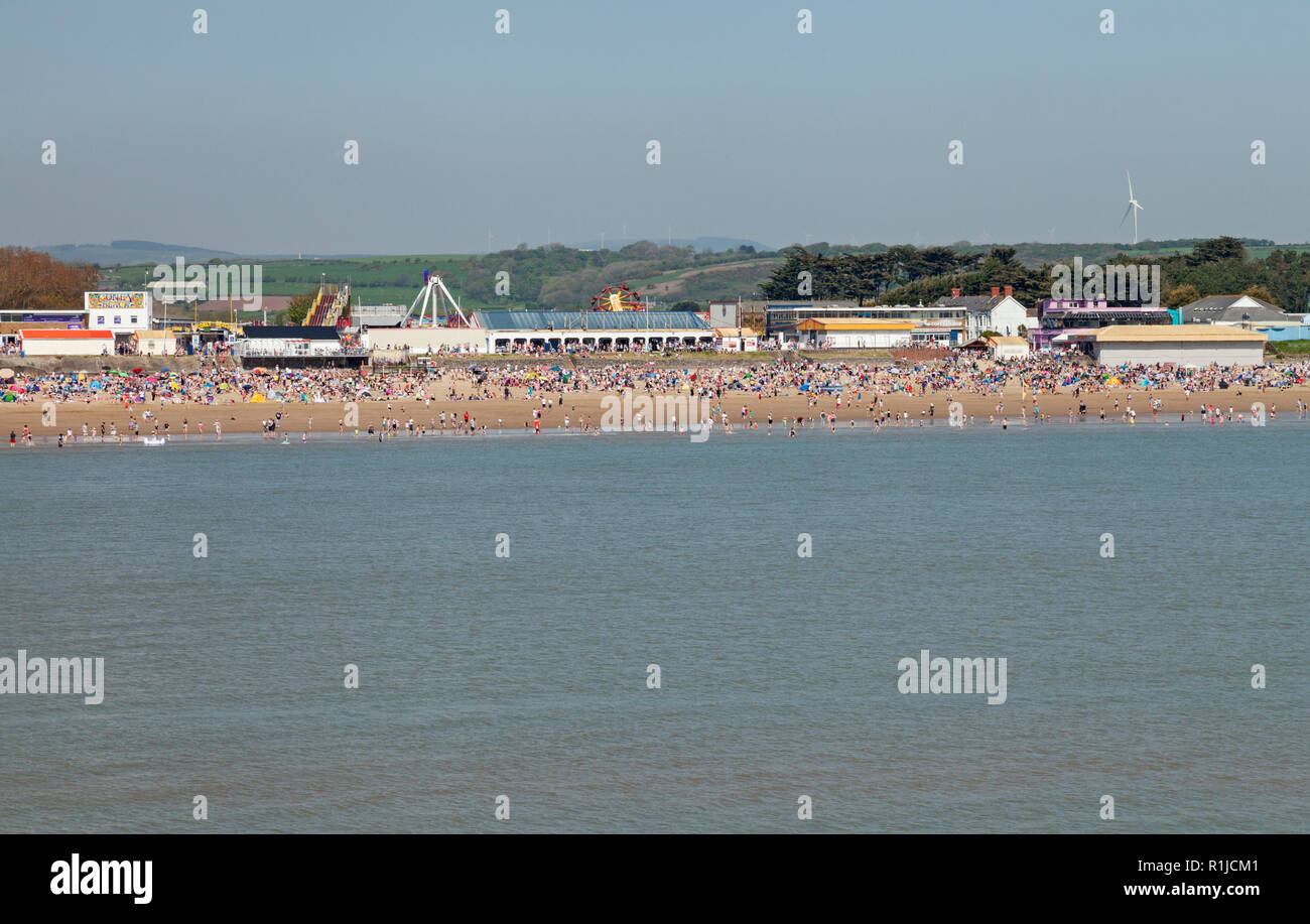 Affollata Bank Holiday Beach a Sandy Bay, con Coney Beach Pleasure Park behiind, Porthcawl, Bridgend, South Wales, Regno Unito Foto Stock