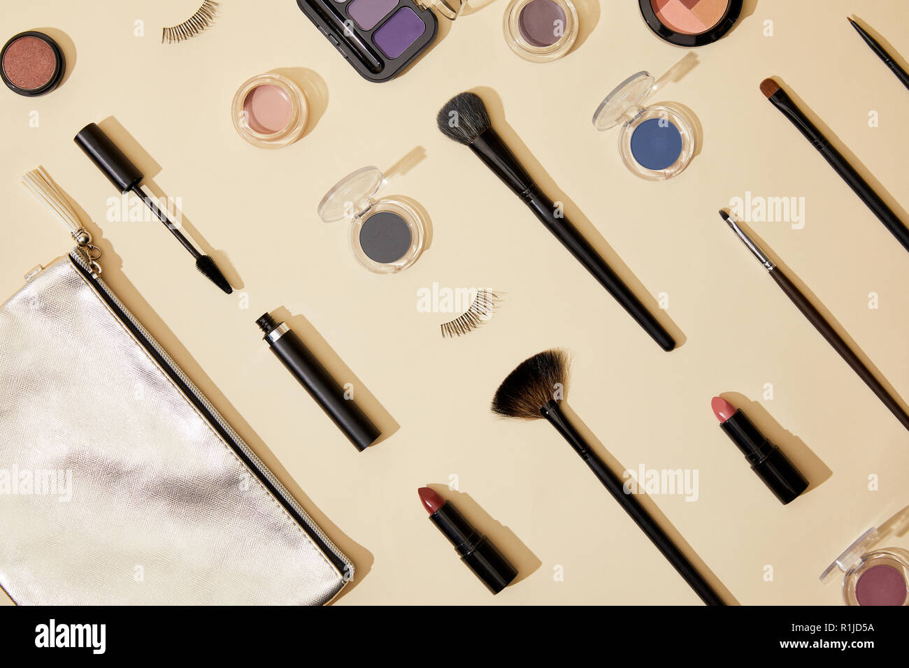 Laici piatta con la composizione di vari cosmetici giacente sulla superficie di colore beige Foto Stock