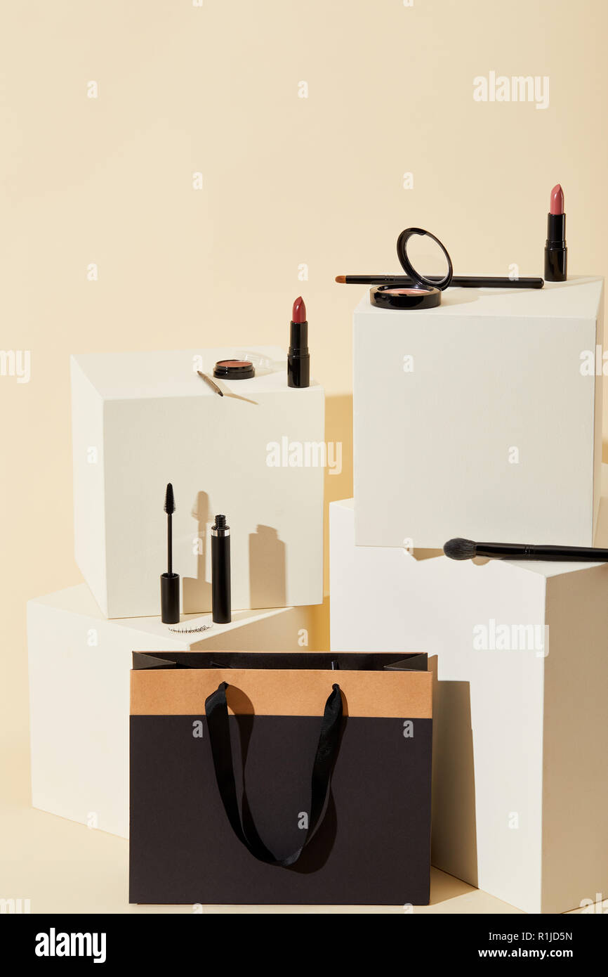 Vari materiali di consumo trucco giacente su cubetti di beige con sacchetto di carta Foto Stock