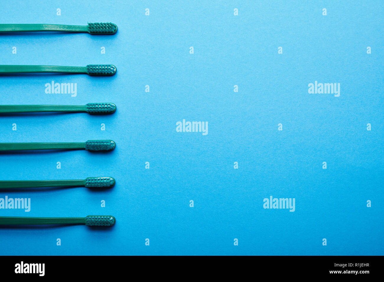 Piatto con laici spazzolini da denti disposti su sfondo blu Foto Stock