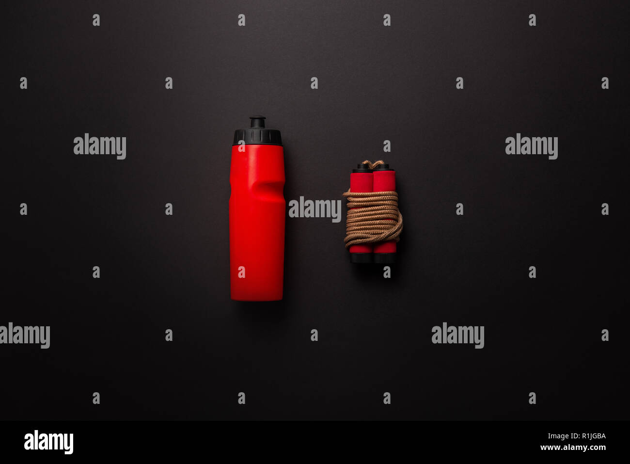 Piatto con laici rosso bottiglia sport e salto con la corda isolato sul nero, concetto minimalista Foto Stock