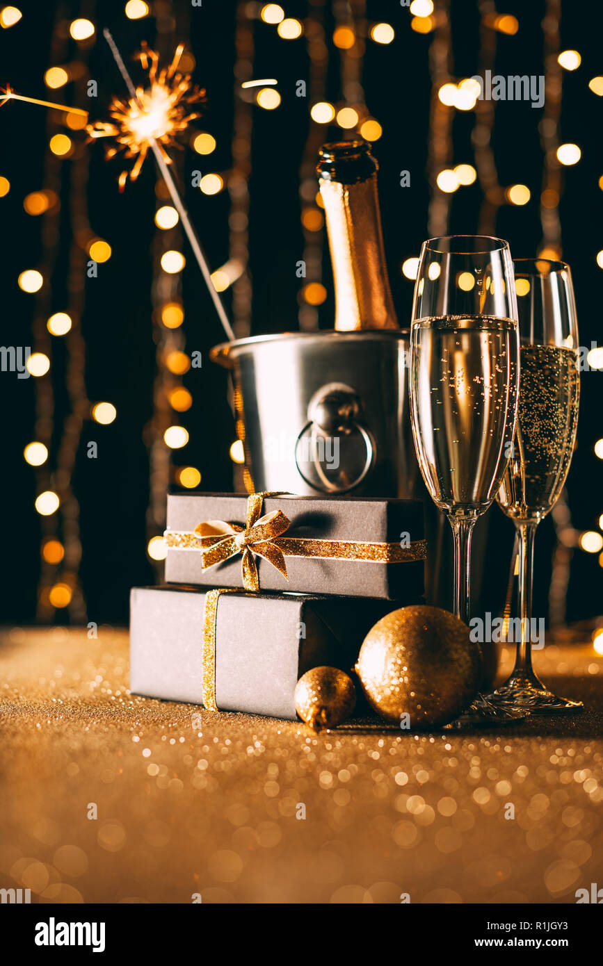 Champagne nella benna presenta e Natale sparkle su garland sfondo luminoso Foto Stock