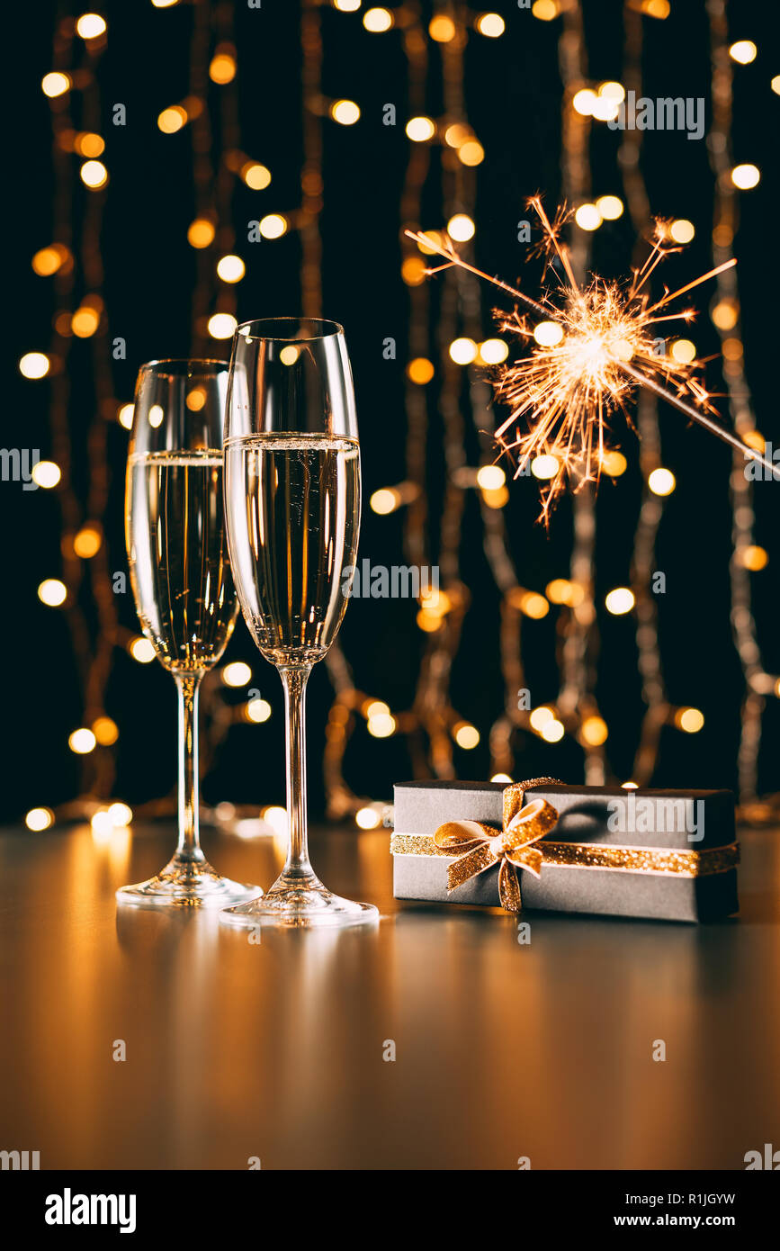 Bicchieri di champagne, presente e Natale sparkle su garland sfondo luminoso, concetto di natale Foto Stock