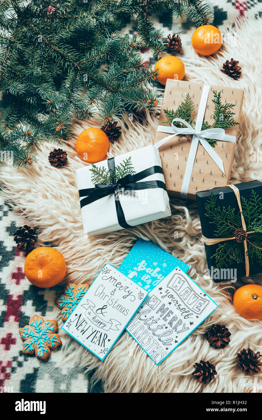 Lay piatto con pino rami, cartoline d'inverno e avvolto i regali di Natale sul fondale di lana Foto Stock