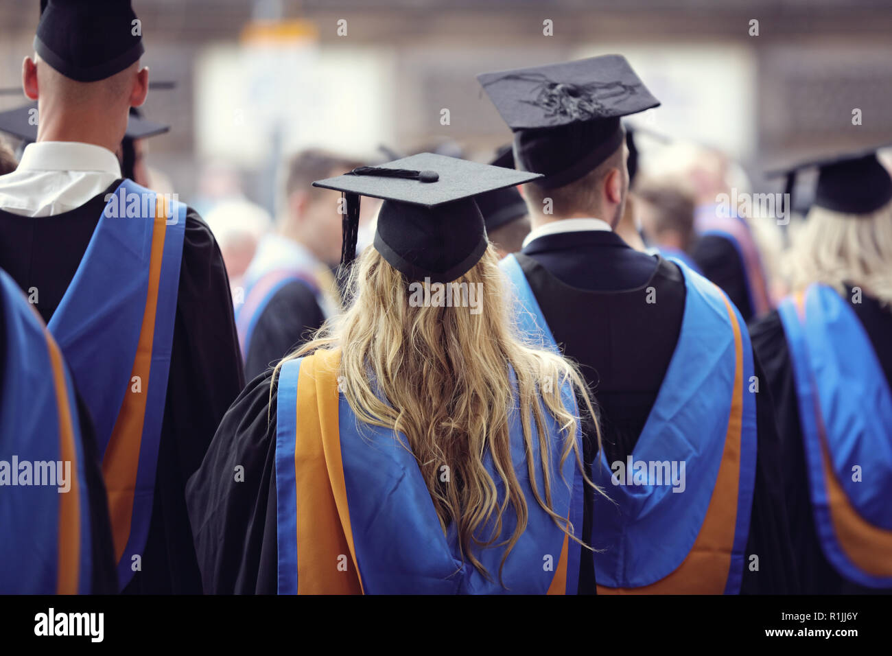 Laureati presso università cerimonia indossando mortarboard e vestaglia Foto Stock