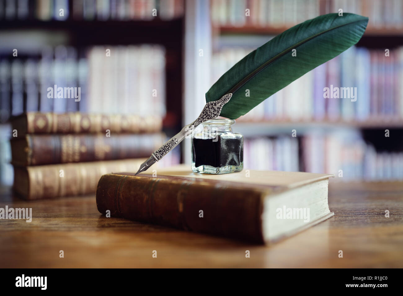 Quill penna e inchiostro ben appoggiato su un vecchio libro in una libreria concetto per la letteratura, la scrittura, autore e storia Foto Stock