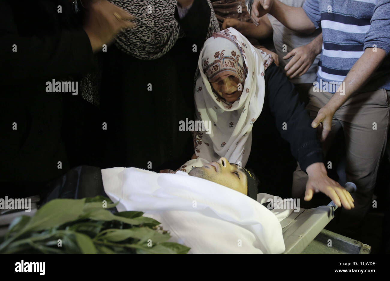 Rafah nella striscia di Gaza, Territori palestinesi. Xii Nov, 2018. I parenti del palestinese Hamad Al Nahhal, che è stato ucciso in un attacco aereo israeliano, piangere sopra il suo corpo durante il suo funerale a Rafah nel sud della striscia di Gaza il 13 novembre 2018. Israele il velivolo colpito Gaza, dopo una valanga di lancio di missili nel suo territorio in provenienza da enclave. Il flare-up è venuto dopo un letale Forze Speciali Israeliane operazione nella Striscia di Gaza nel weekend Credito: Ramadan Elagha APA/images/ZUMA filo/Alamy Live News Foto Stock