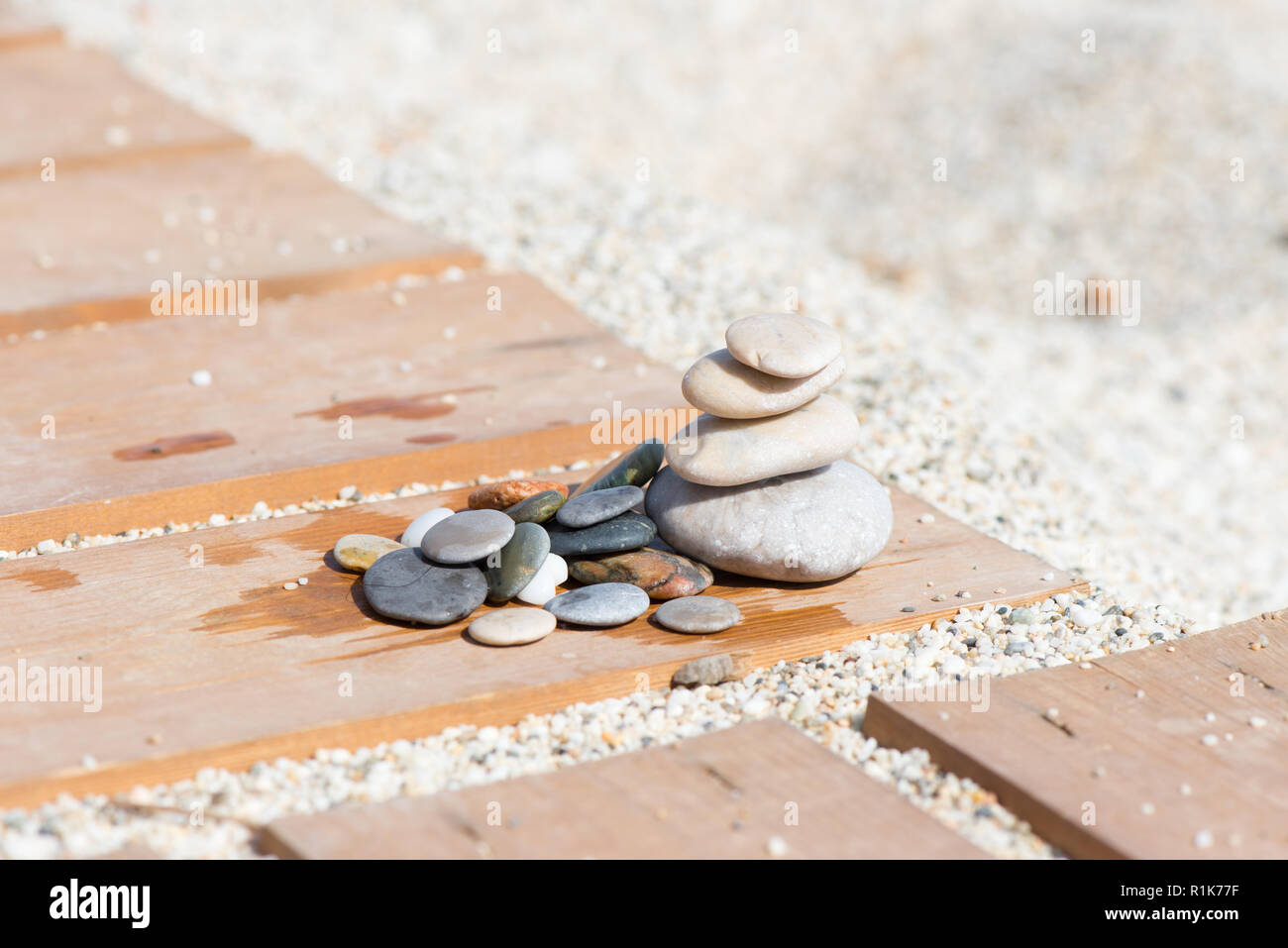 Disposizione con pietre di assicelle di legno sulla sabbia di una spiaggia Foto Stock