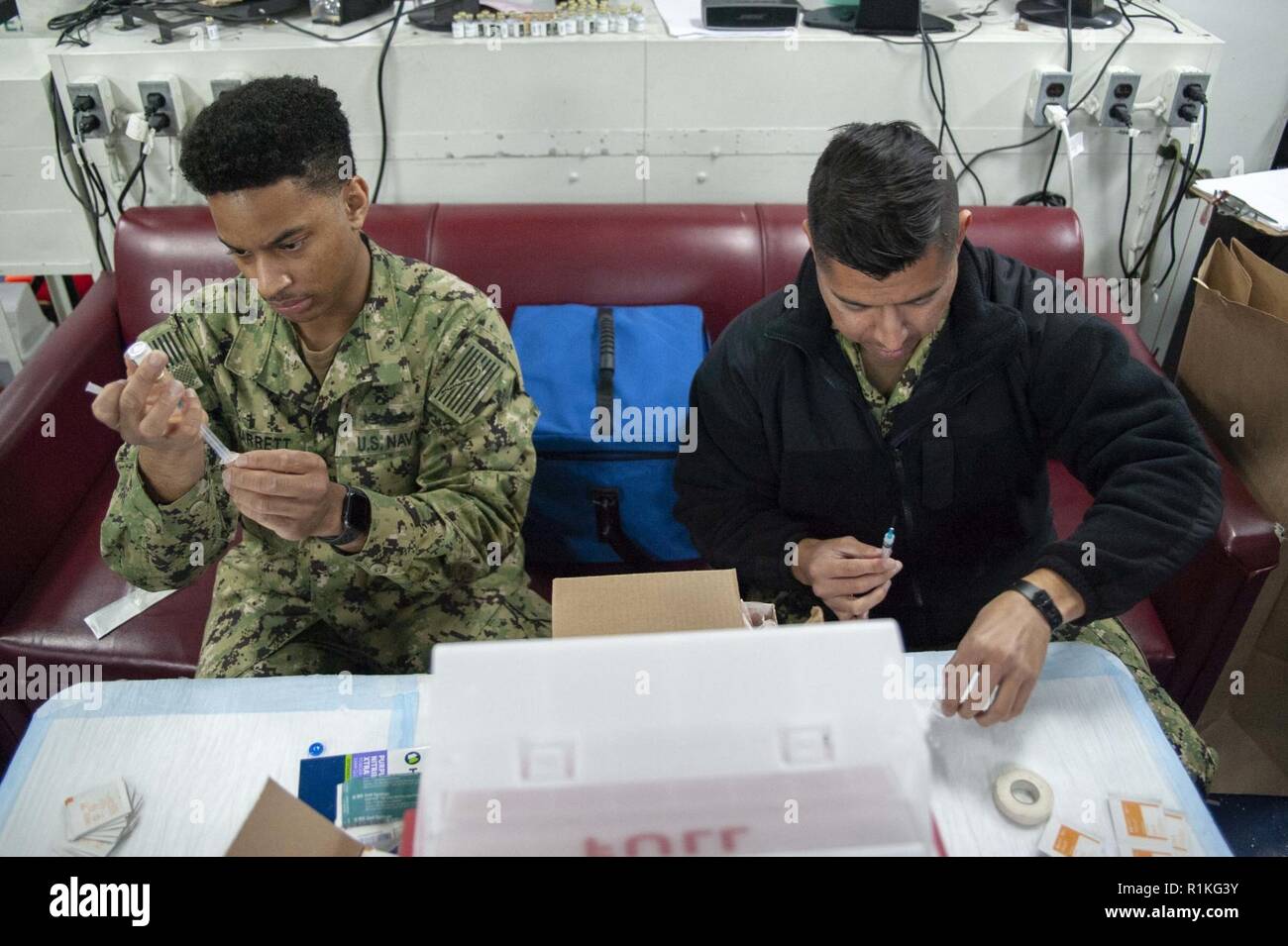 SAN DIEGO (ott. 16, 2018) Ospedale Corpsman 2a classe Nathaniel Garrett, sinistra, da St. Louis, e Hospitalman Emmanuel Flores, da Chicago, preparare le siringhe durante il virus influenzale vaccinazioni a bordo dell'assalto anfibio nave USS Bonhomme Richard (LHD 6). Bonhomme Richard è nel suo homeport di San Diego. Foto Stock