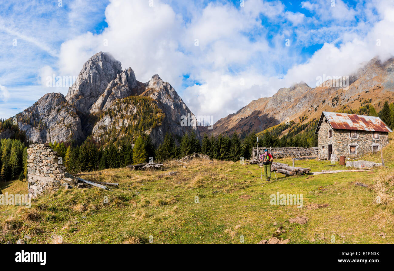 Paesaggio di montagna con cielo blu con nuvole e le rovine di una vecchia fattoria e un escursionista Foto Stock