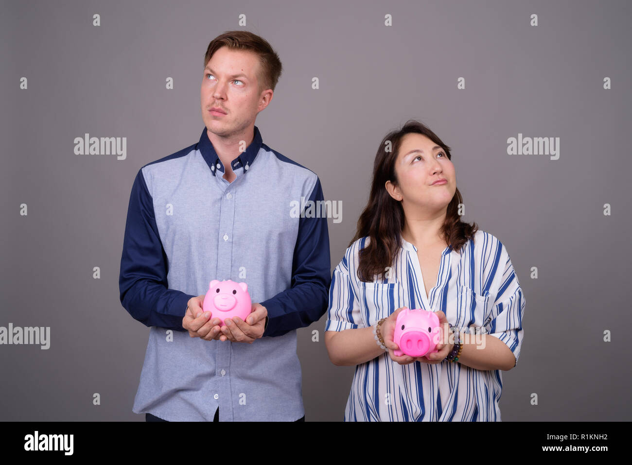 Ritratto di giovane azienda salvadanaio in mano mentre pensando Foto Stock