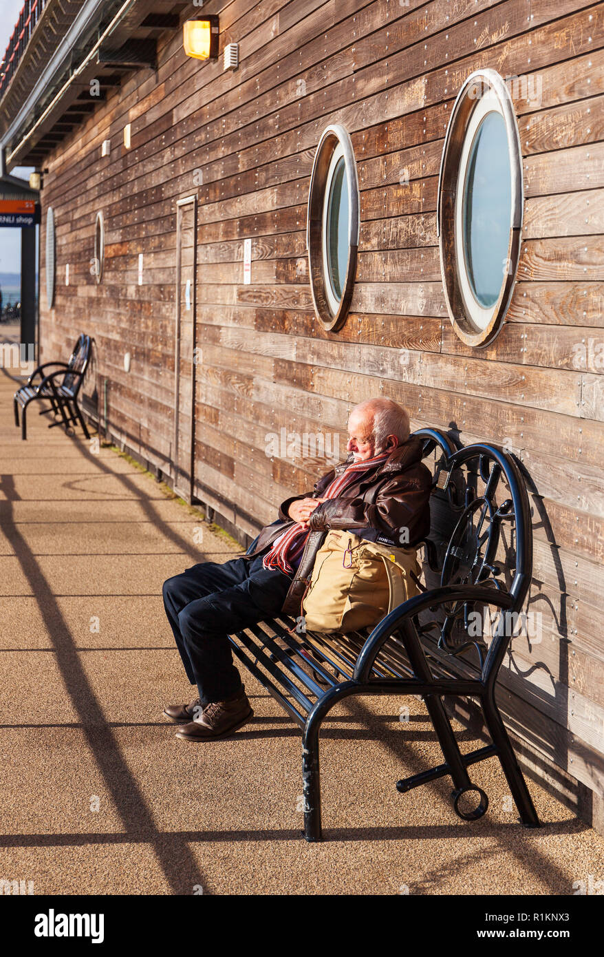 Senior uomo dorme sotto il sole sul molo di Southend. Foto Stock