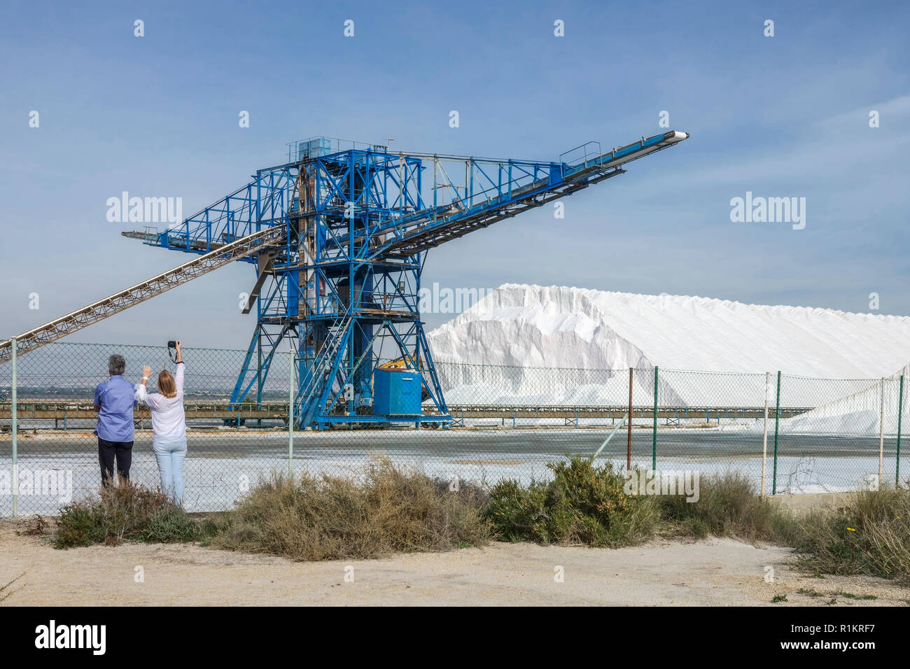 Il sale spagnolo lavora a Santa Pola. Cumulo di sale marino e macchina industriale, provincia di Alicante, coppia di persone che scattano foto in Costa Blanca Spagna Foto Stock