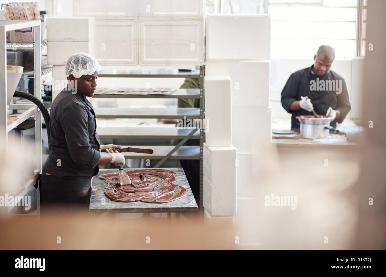 Lavoratore di cioccolato di miscelazione in una confetteria rendendo la fabbrica Foto Stock