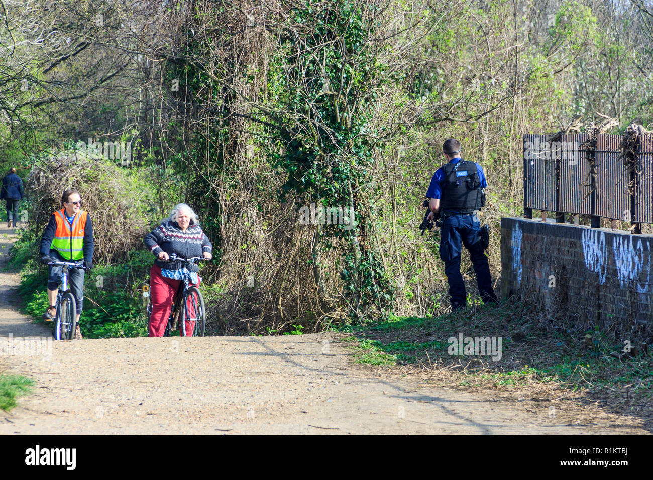 Un agente di polizia armato sorprese i ciclisti sul Parco a piedi, un pubblico sentiero natura nel nord di Londra, Regno Unito, su un pomeriggio di primavera Foto Stock