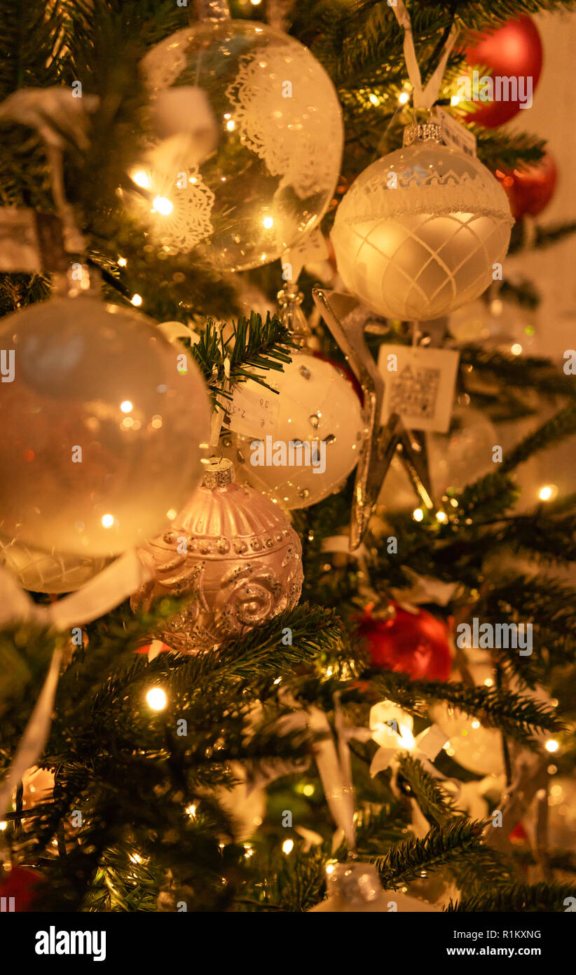 Assortimento di colori bianco e argento palla di Natale ornamenti su albero con luci Foto Stock