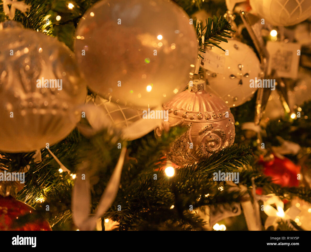 Assortimento di colori bianco e argento palla di Natale ornamenti su albero con luci Foto Stock