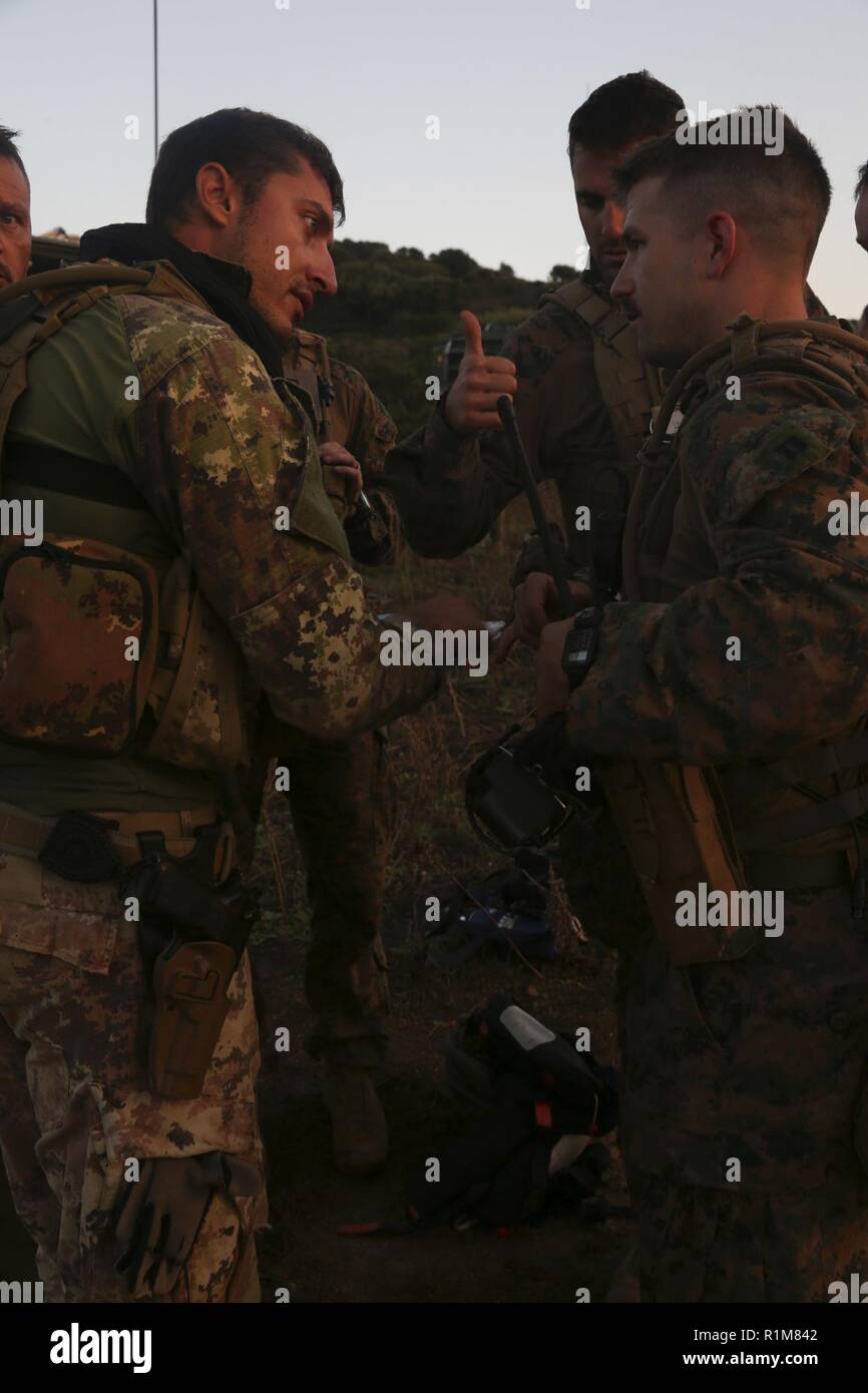 Sardegna, Italia (ott. 12, 2018) DEGLI STATI UNITI Marine Capt. Robert Atkinson, a destra il comandante di plotone per la forza della ricognizione Det. del Battaglione Team di atterraggio 3/1, 13 Marine Expeditionary Unit (MEU), parla di Navale Italiana fante, Alex Semararo, dopo una nave-shore assalto anfibio durante la fase di esercizio la Mare Aperto, Ottobre 12, 2018. La Mare Aperto è progettato per migliorare la combinata di capacità di combattimento, aumentare la capacità operativa e di rafforzare le relazioni tra i partecipanti di esercizio. Foto Stock