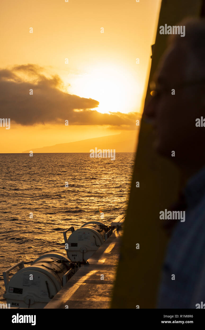 Tramonto sull'isola di La Gomera visto dal ponte di un traghetto Inter Island con la scialuppa di salvataggio pod in primo piano, Tenerife, Isole Canarie, Spagna Foto Stock