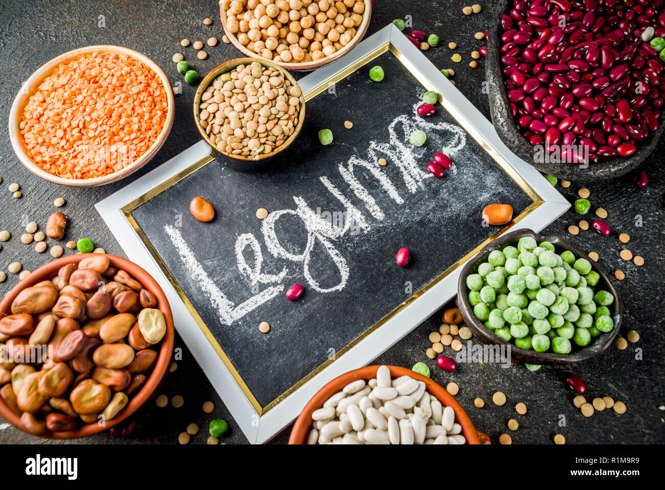 Vario assortimento di legumi - fagioli di soia, fagioli, ceci, lenticchie piselli verdi. Mangiare sano concetto. Proteine vegetali. Scuro dello sfondo in calcestruzzo Foto Stock