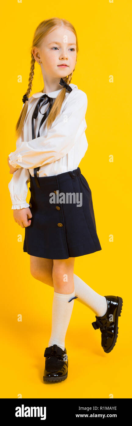 Ragazza con pigtail di colore rosso su sfondo giallo. Una bella ragazza è in piedi con il suo piede. Foto Stock