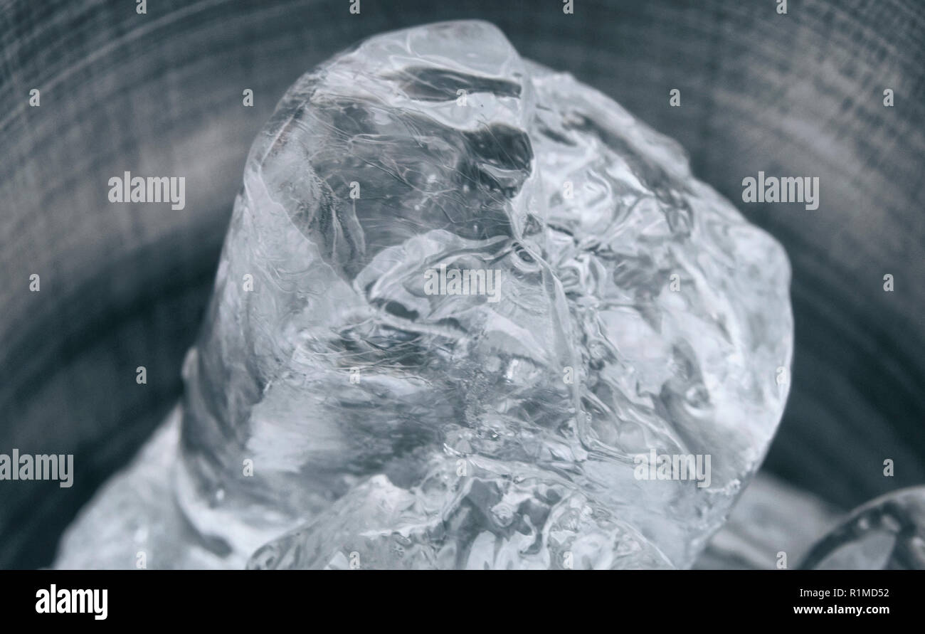 Pezzo di ghiaccio in una tazza di stagno un background in metallo Foto Stock