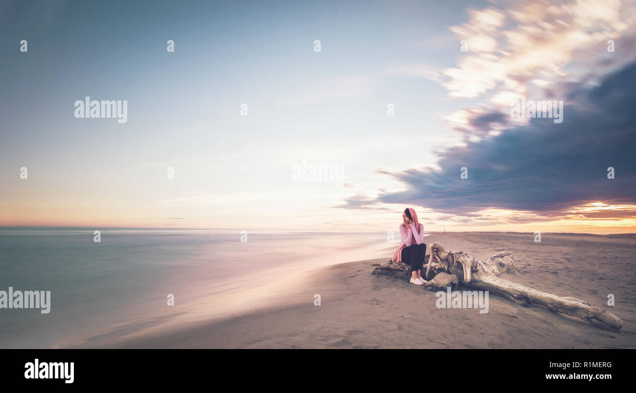 Donna seduta dall'oceano su una spiaggia di Paradise Island, circondato dal paradiso, bel tramonto o l'alba Foto Stock