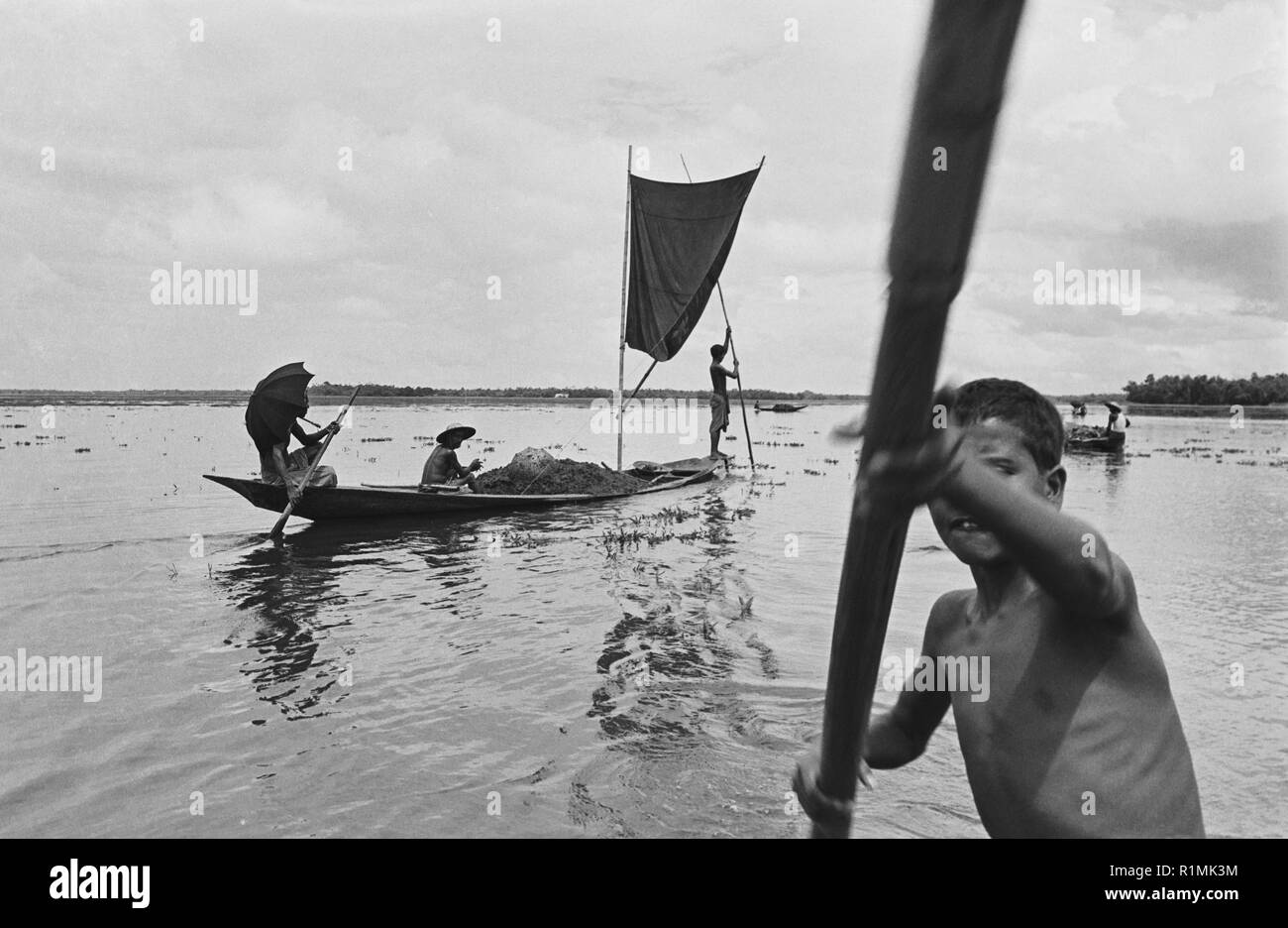 35/13 Boy lottando al Polo battello attraverso giacinto di acqua 1980 Foto Stock
