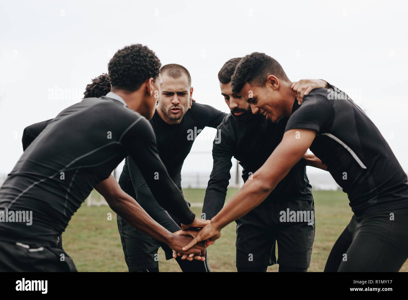Giocatori di calcio che si uniscono per mano in un huddle parlando della strategia di gioco. i calciatori si piegano in avanti in un huddle tenendosi per mano. Foto Stock
