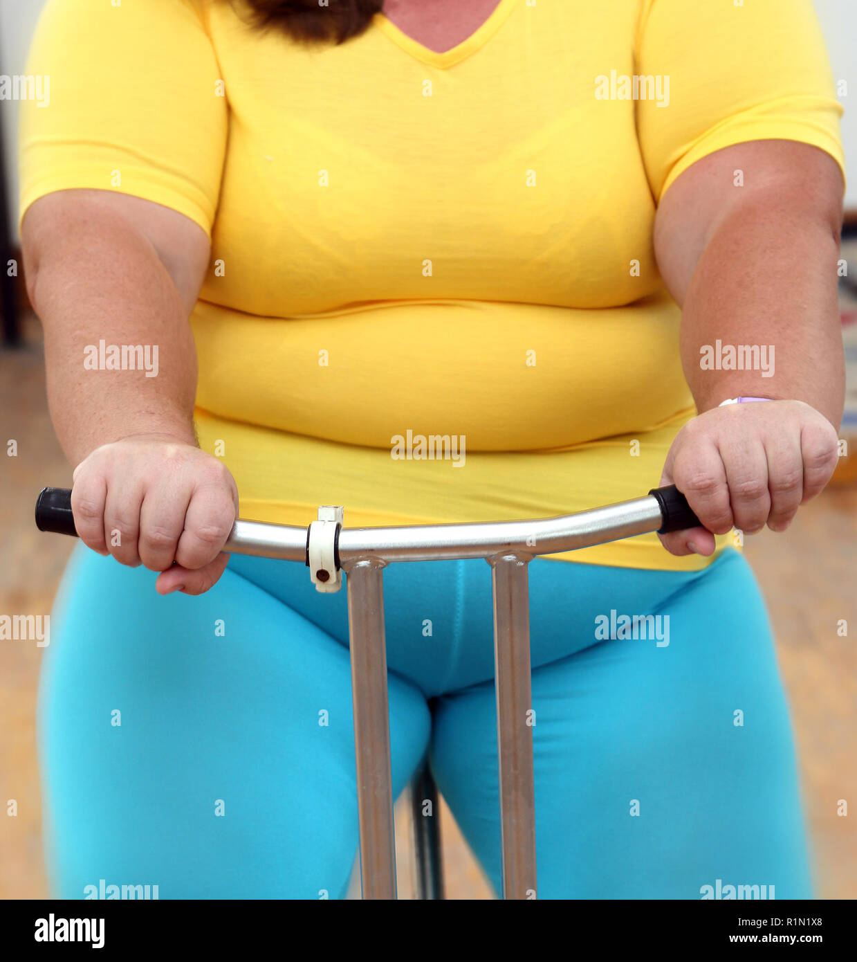 Il sovrappeso donna esercita sul simulatore di bici Foto Stock