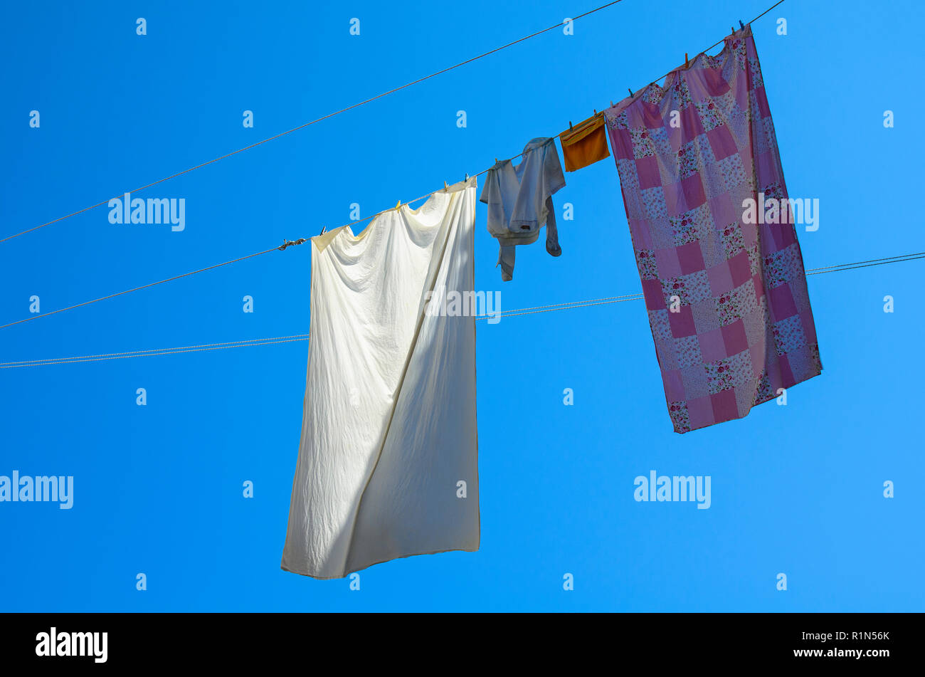 Pigiami e fogli appesi da una filettatura nella parte anteriore di una soluzione satura di cielo blu per asciugare Foto Stock