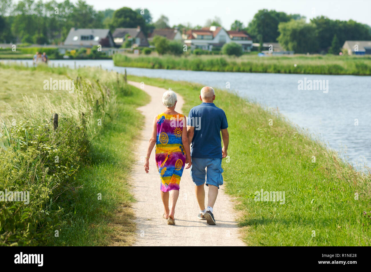 Coppia di anziani e di una famiglia passeggiate lungo il lato de canal de Eem a Baarn e godendo di una calda giornata estiva, Paesi Bassi Foto Stock