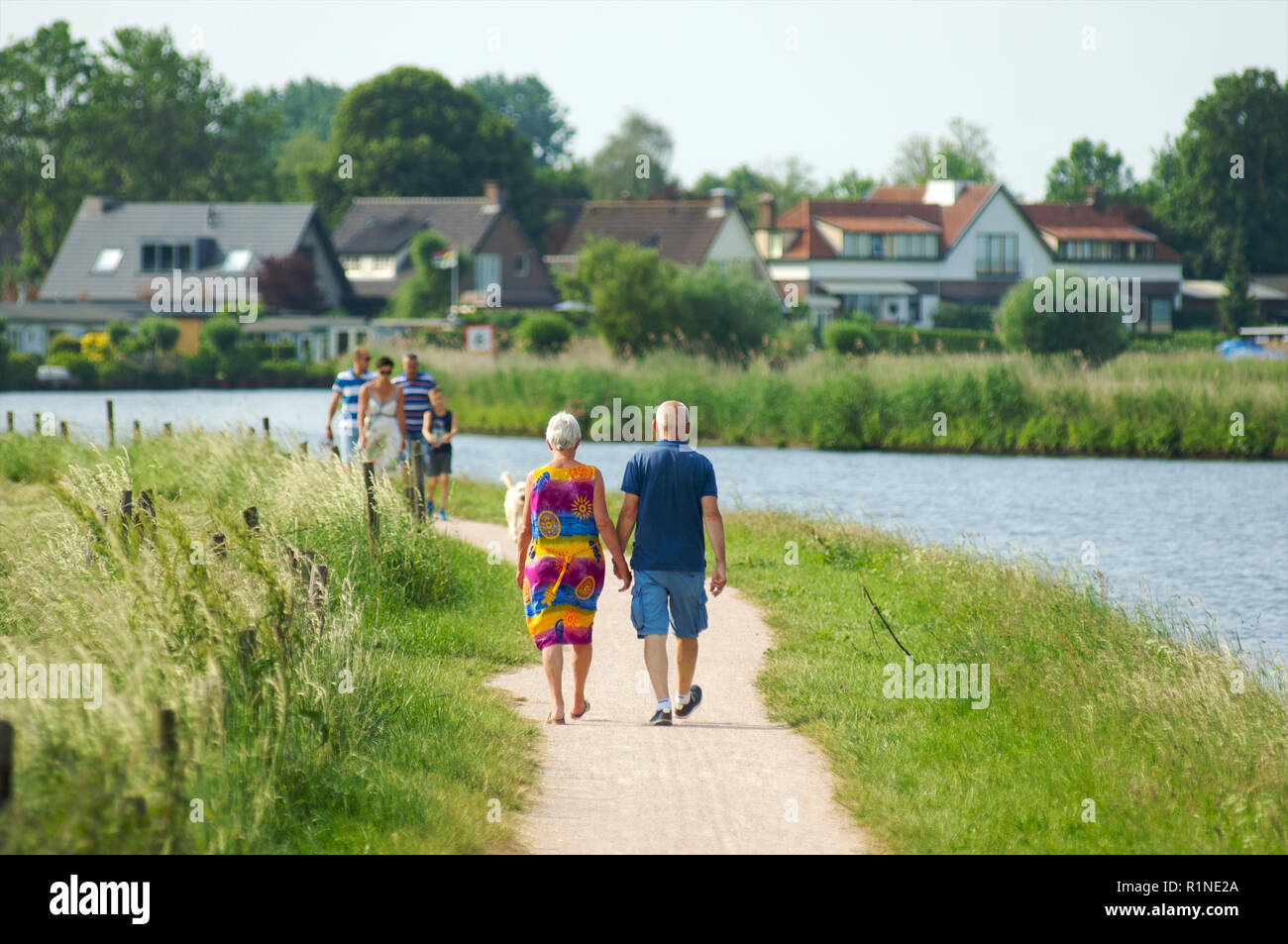 Coppia di anziani e di una famiglia passeggiate lungo il lato de canal de Eem a Baarn e godendo di una calda giornata estiva, Paesi Bassi Foto Stock