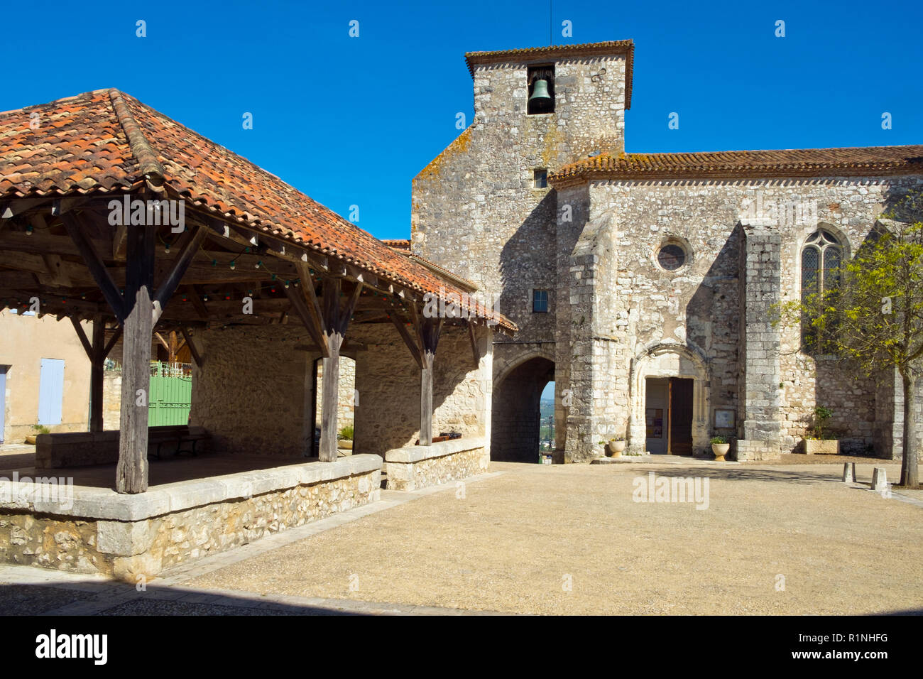 Il mercato coperto e la chiesa in srping sunshine a Pujols, Lot-et-Garonne, Francia. Questo storico villaggio fortificato di Rocca è ora un membro del "Les Plus Beaux Villages de France' Association. Foto Stock