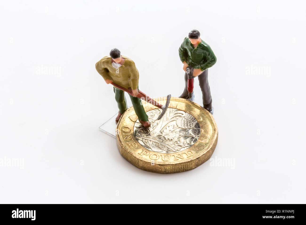 La fabbricazione o la distruzione di denaro. Pound moneta con operai in miniatura. Foto Stock
