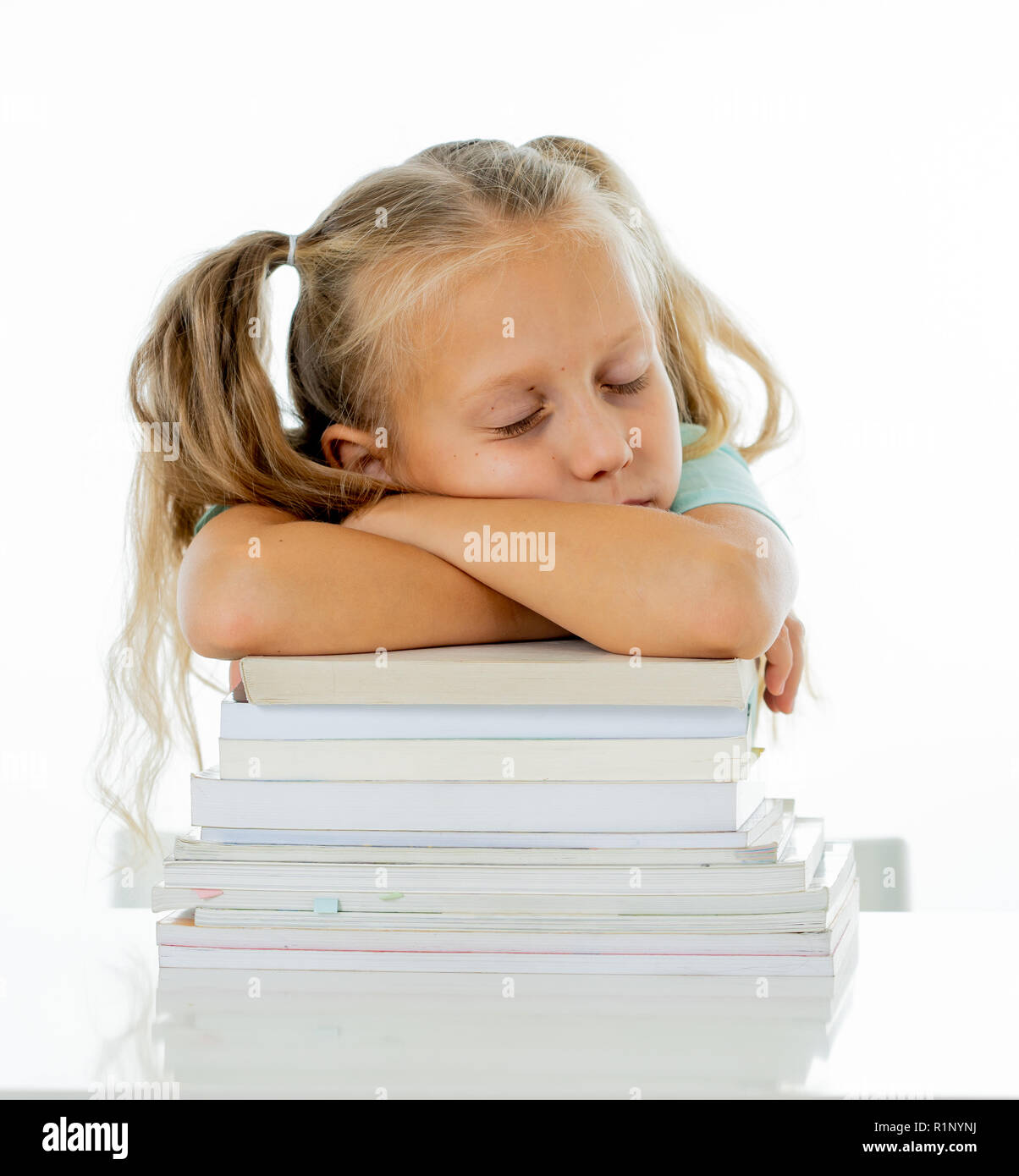 Esaurito il dolce carina ragazza bionda di dormire su una pila di libri scolastici dopo essere state studiando hard isolato su uno sfondo bianco in modo troppo learning premere Foto Stock