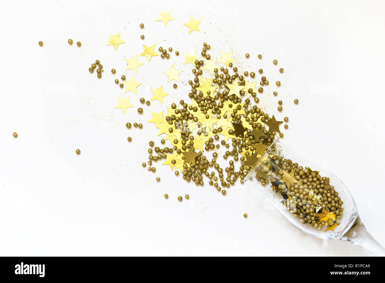 Golden coriandoli a forma di stelle effuso bicchieri di champagne su bianco. Vista dall'alto. Festa di Natale. Notte magica. Foto Stock