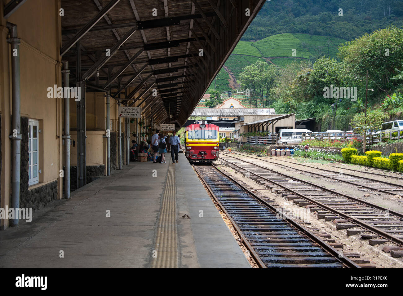 Per Nanu-Oya Ella treno in arrivo. Considerato uno dei più conica viaggi ferroviari in tutto il mondo. Il rosso e il giallo carrello attende alla piattaforma. Foto Stock