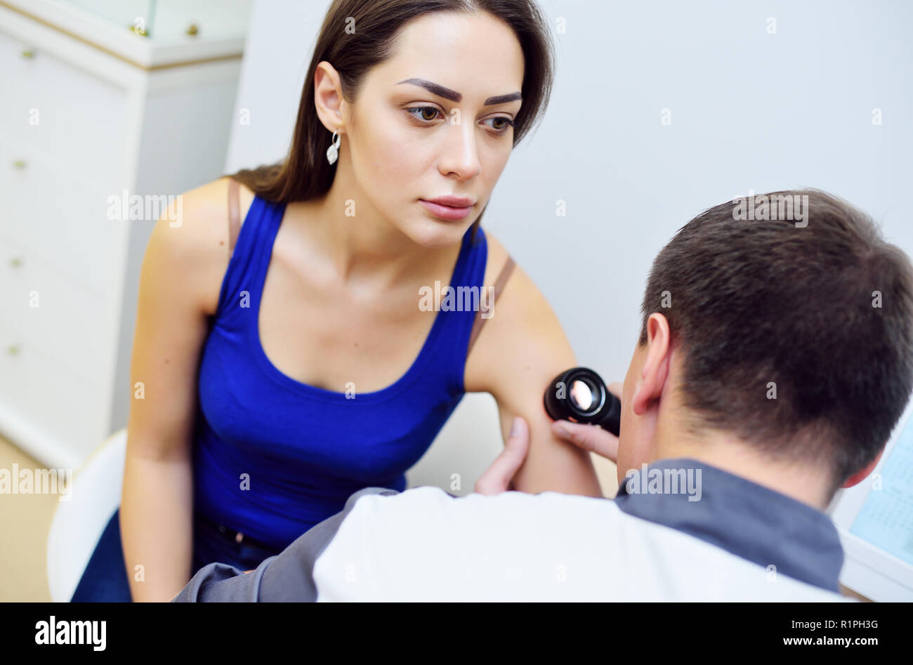 Medico dermatologo esamina la pelle della ragazza del paziente per la presenza di moli, birthmarks, tumori. Dermatoscopy, prevenzione del melanoma, pelle Foto Stock