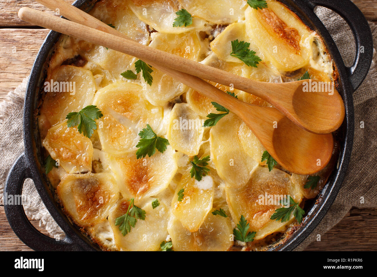 Janssonin Kiusaus patate al forno con i filetti di acciuga, cipolle e panna in una padella sul tavolo. parte superiore orizzontale vista da sopra. Pinna Foto Stock